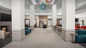 A spacious lobby with a fireplace, seating areas, and a central kitchen. - Hilton Garden Inn Colorado Springs North Air Force Academy (Colorado Springs)