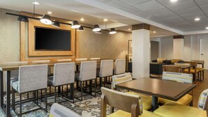 Une salle à manger d’hôtel avec une longue table, de nombreuses chaises et un éclairage suspendu au plafond.