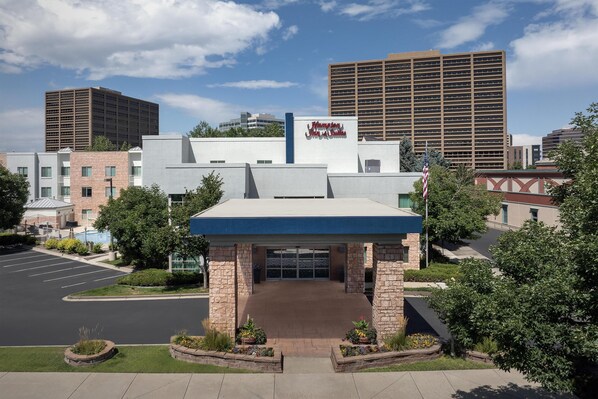 A hotel entrance with a blue roof, stone facade, and a parking lot. - Hampton Inn & Suites Denver Tech Center (Denver)