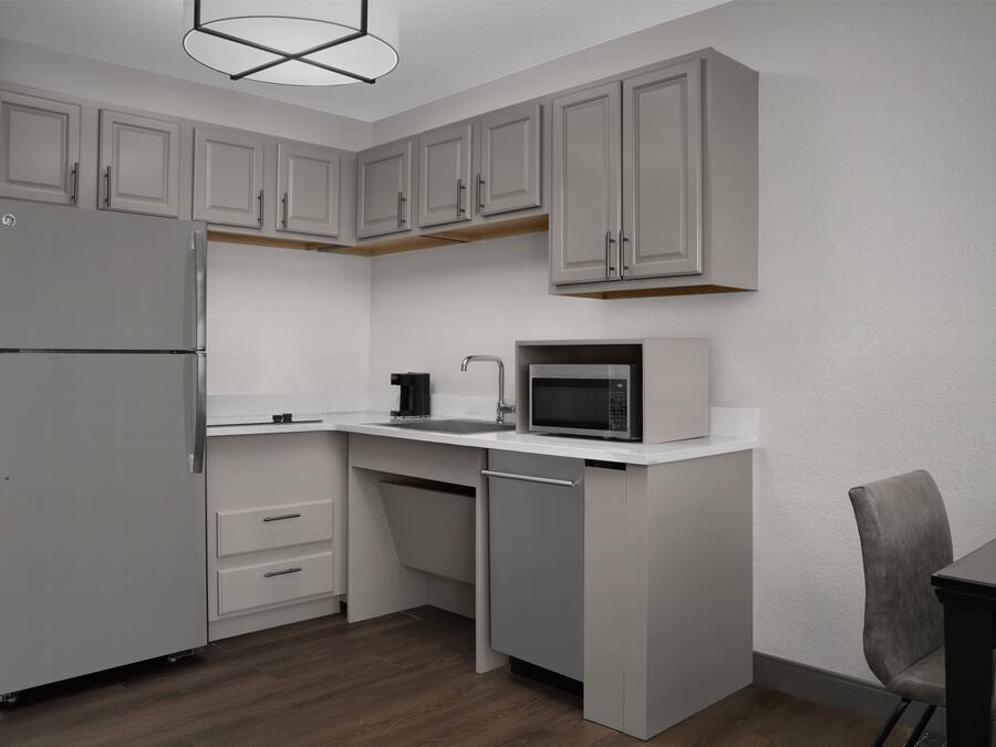 A compact kitchen with a refrigerator, microwave, and sink.