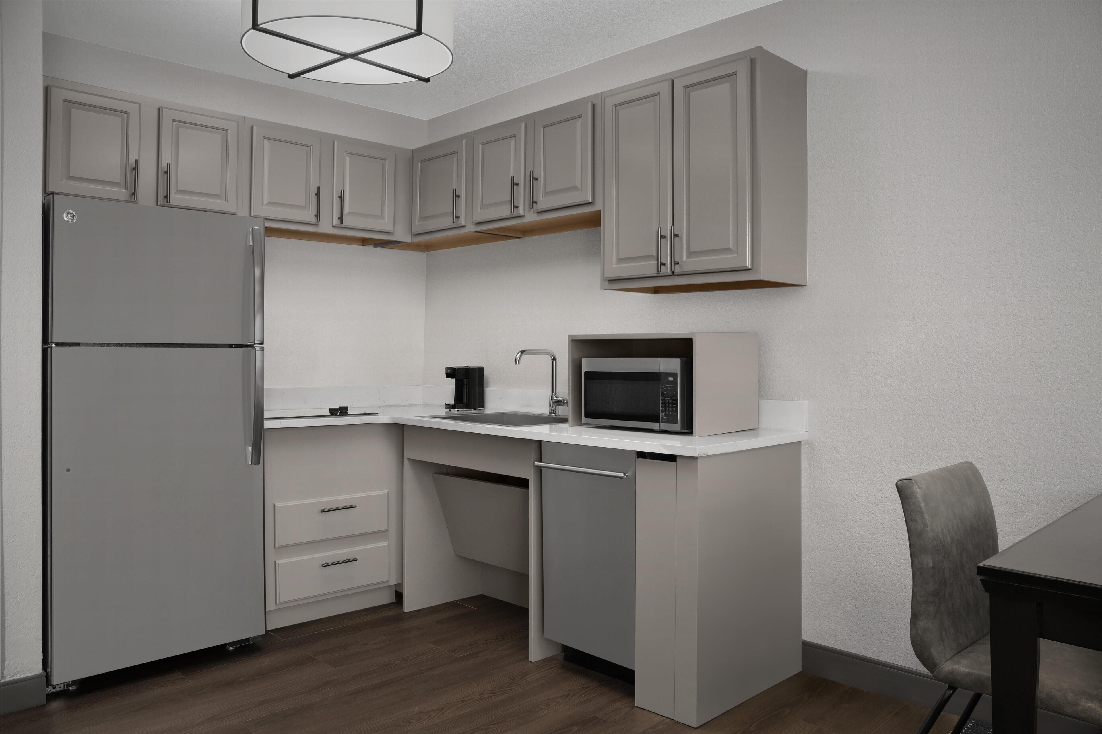 A compact kitchen with a refrigerator, microwave, and sink.