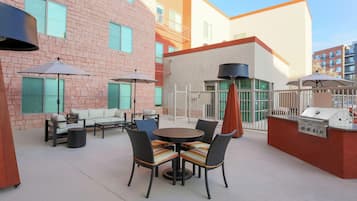 An outdoor patio area with a round table and chairs, a sofa, and umbrellas.