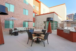 An outdoor patio area with a round table and chairs, a sofa, and umbrellas. - Hampton Inn & Suites Denver Tech Center (Denver)