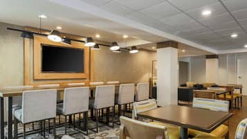 A hotel dining area with a long table, multiple chairs, and overhead lighting.
