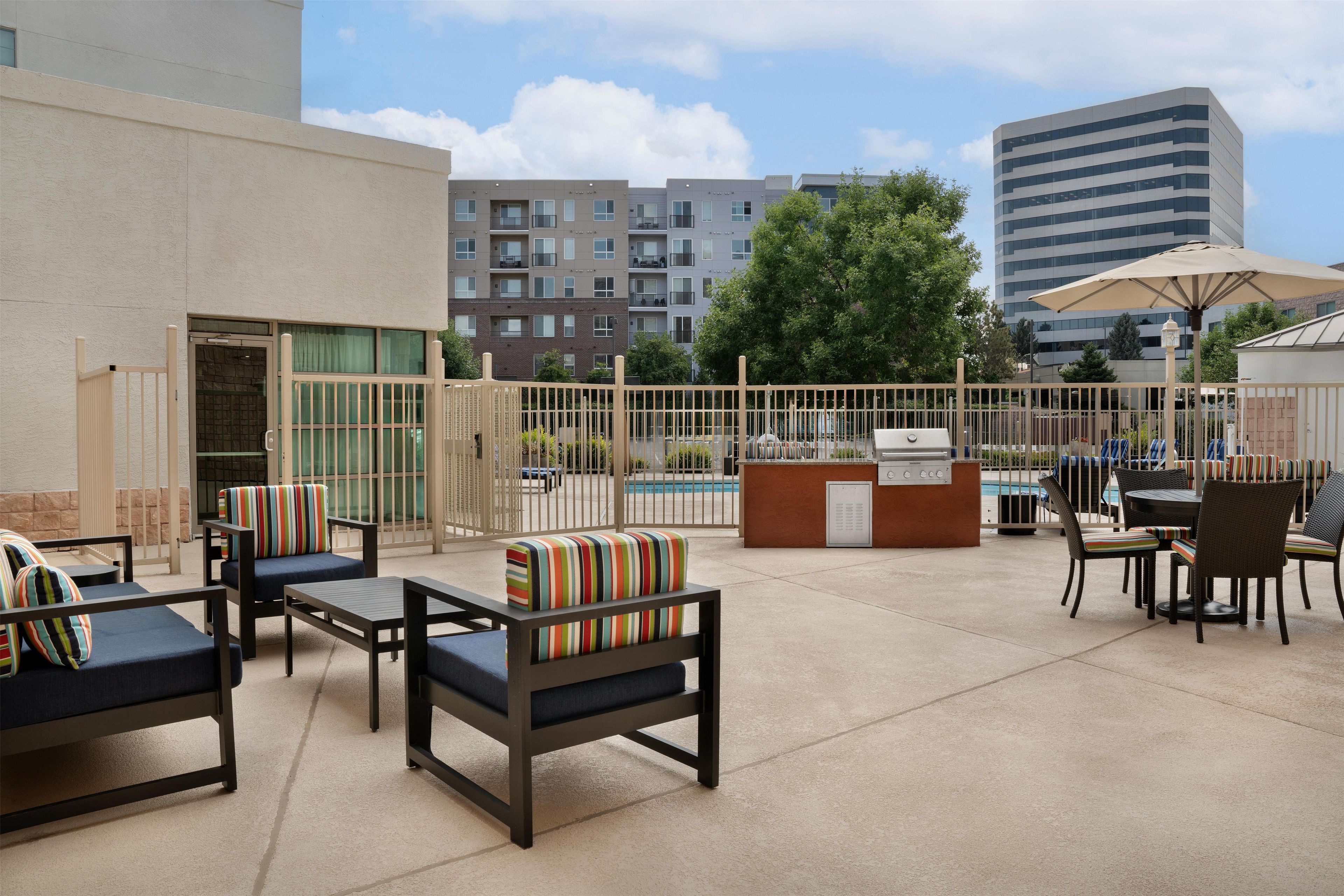 Un patio exterior con asientos, piscina y zona de bar.