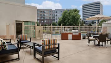 Un patio exterior con asientos, piscina y zona de bar.