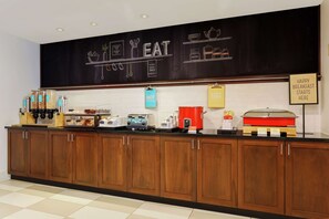 A breakfast bar with a chalkboard sign reading "EAT HERE" and various food items and appliances.