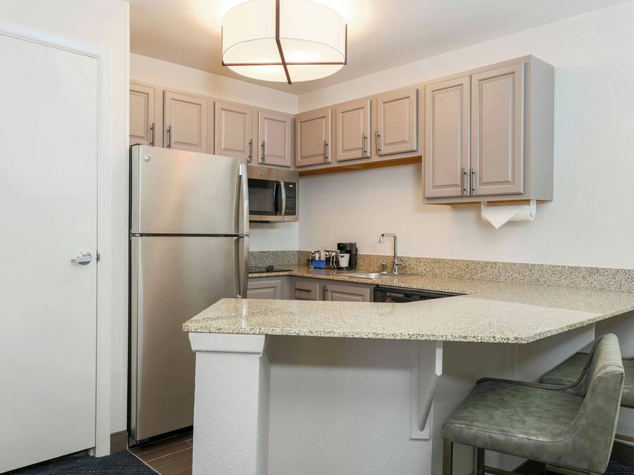 A compact kitchen with a built-in refrigerator, microwave, and a small island with seating.