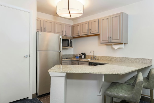 A compact kitchen with a built-in refrigerator, microwave, and a small island with seating.