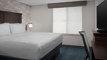 Quarto de hotel com uma cama grande, televisão, escrivaninha e janela com vista.