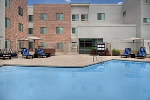 A pool area with lounge chairs and umbrellas, surrounded by a brick building with multiple windows. - Hampton Inn & Suites Denver Tech Center (Denver)