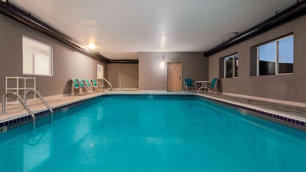 An indoor swimming pool with clear blue water, surrounded by lounge chairs and a door.