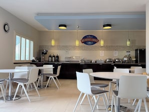 A breakfast area with tables and chairs, a coffee machine, and a sign for 'Baymont Breakfast Corner'.