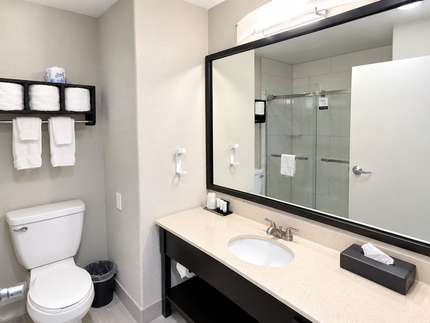 Un baño moderno con inodoro, lavabo y un espejo grande.