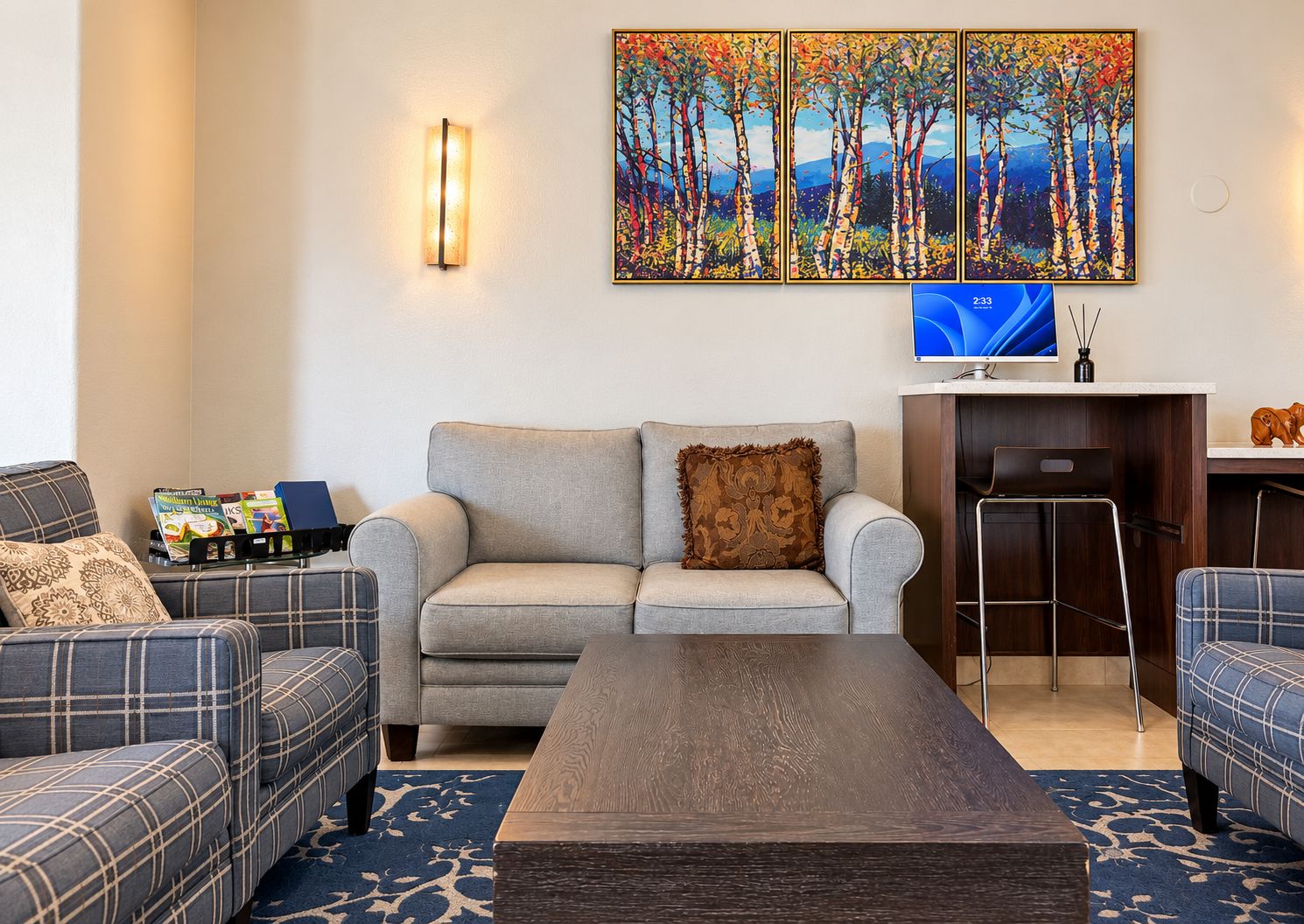 A living room with a sofa, a coffee table, and a TV. There are books and decorative items on the sofa.