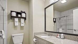 A bathroom with a toilet, a sink, a mirror, and a towel rack with towels.