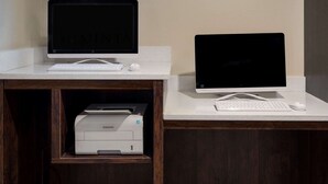 Two desktop computers on a white desk with a printer below.