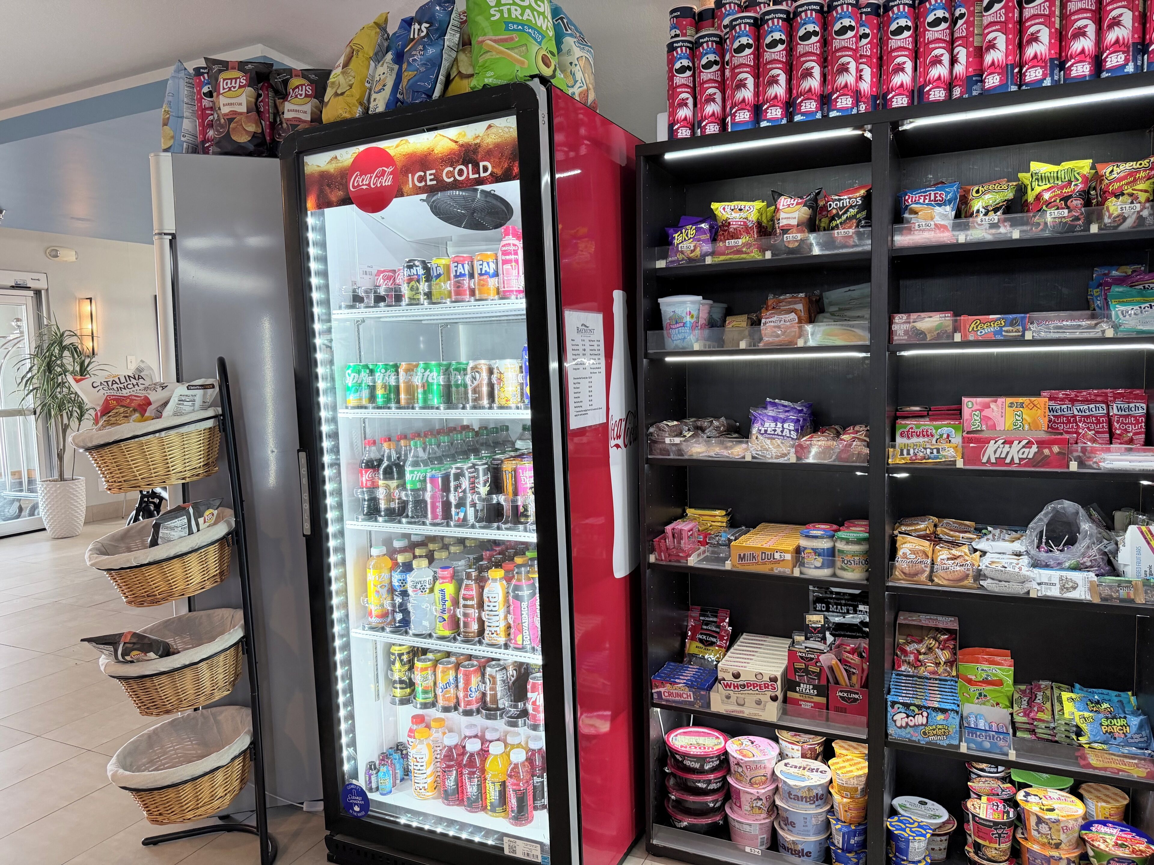 A vending machine stocked with beverages and snacks, adjacent to shelves with packaged goods.