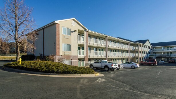 Un motel à plusieurs étages avec un parking, un poteau d’incendie et un ciel dégagé.