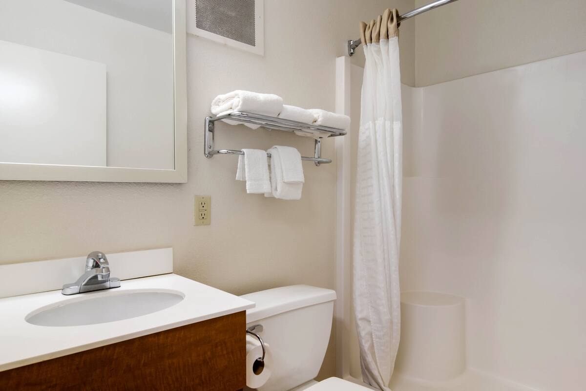 Een badkamer met een wastafel, spiegel, handdoekhouder, toilet en douchegordijn.