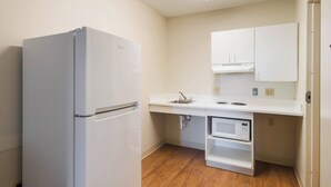 A compact kitchen with a refrigerator, microwave, sink, and cabinets. - HomeTowne Studios by Red Roof Denver - Thornton (Thornton)