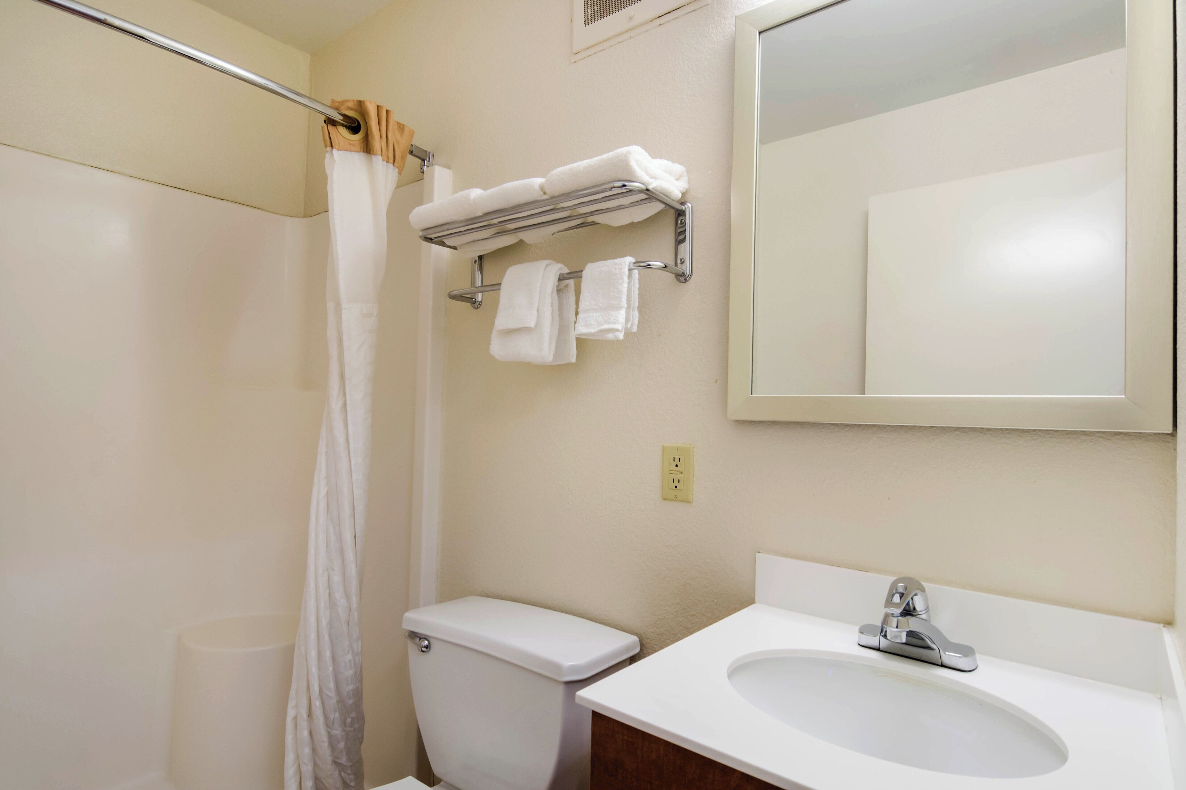 A bathroom with a toilet, sink, and a towel rack with towels.