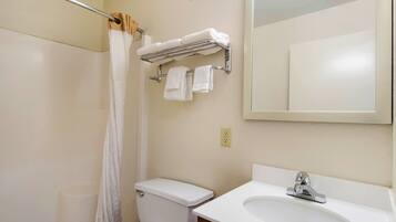 A bathroom with a toilet, sink, and a towel rack with towels.