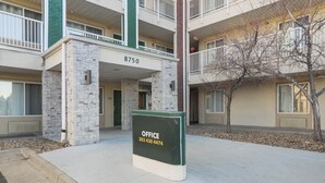 Un immeuble avec une façade en pierre, un balcon et une enseigne indiquant qu’il s’agit d’un bureau, avec un numéro de téléphone.