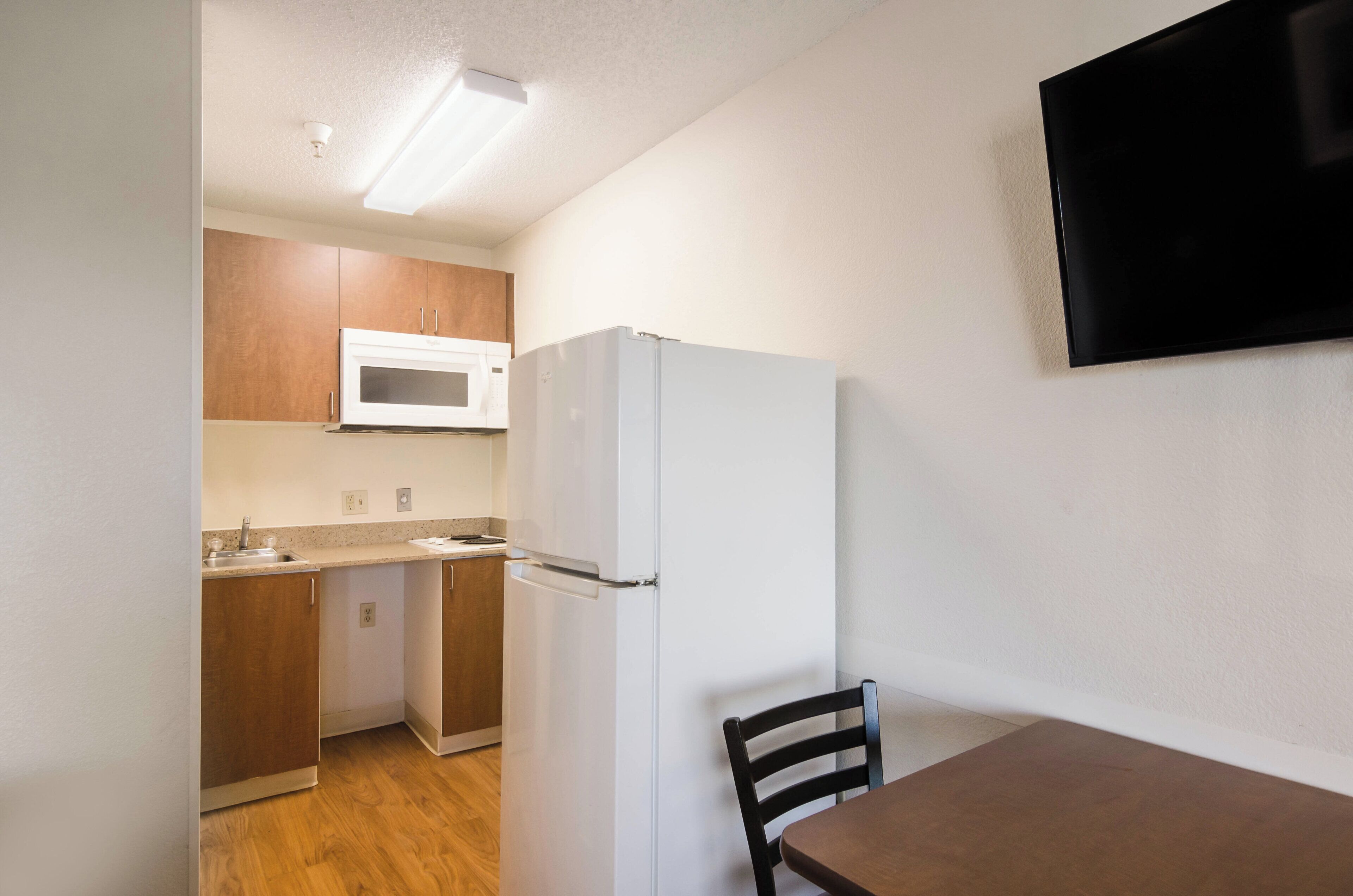 Una cocina compacta con microondas, refrigerador y armarios de madera.