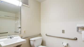 Un baño con lavamanos blanco, inodoro, espejo y pasamanos.