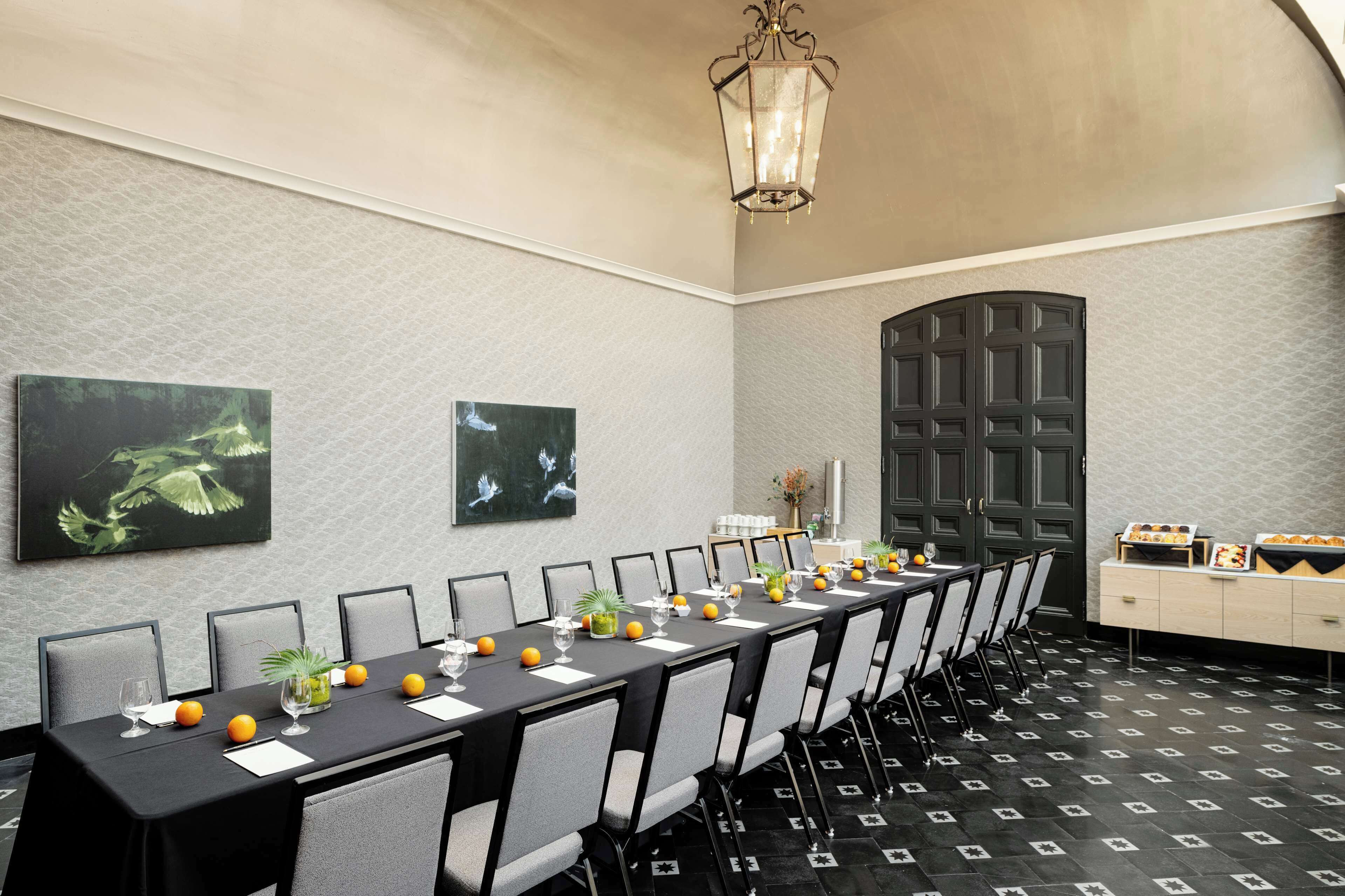 Un salón de conferencias con una larga mesa, sillas y una lámpara decorativa.