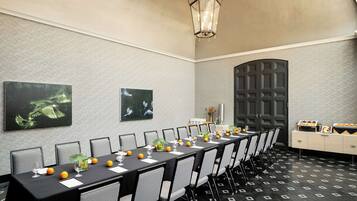 Une salle de conférence équipée d’une longue table, de chaises et d’un luminaire décoratif.