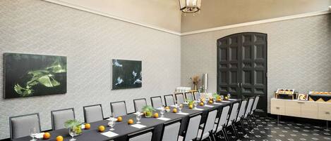 Un salón de conferencias con una larga mesa, sillas y una lámpara decorativa.