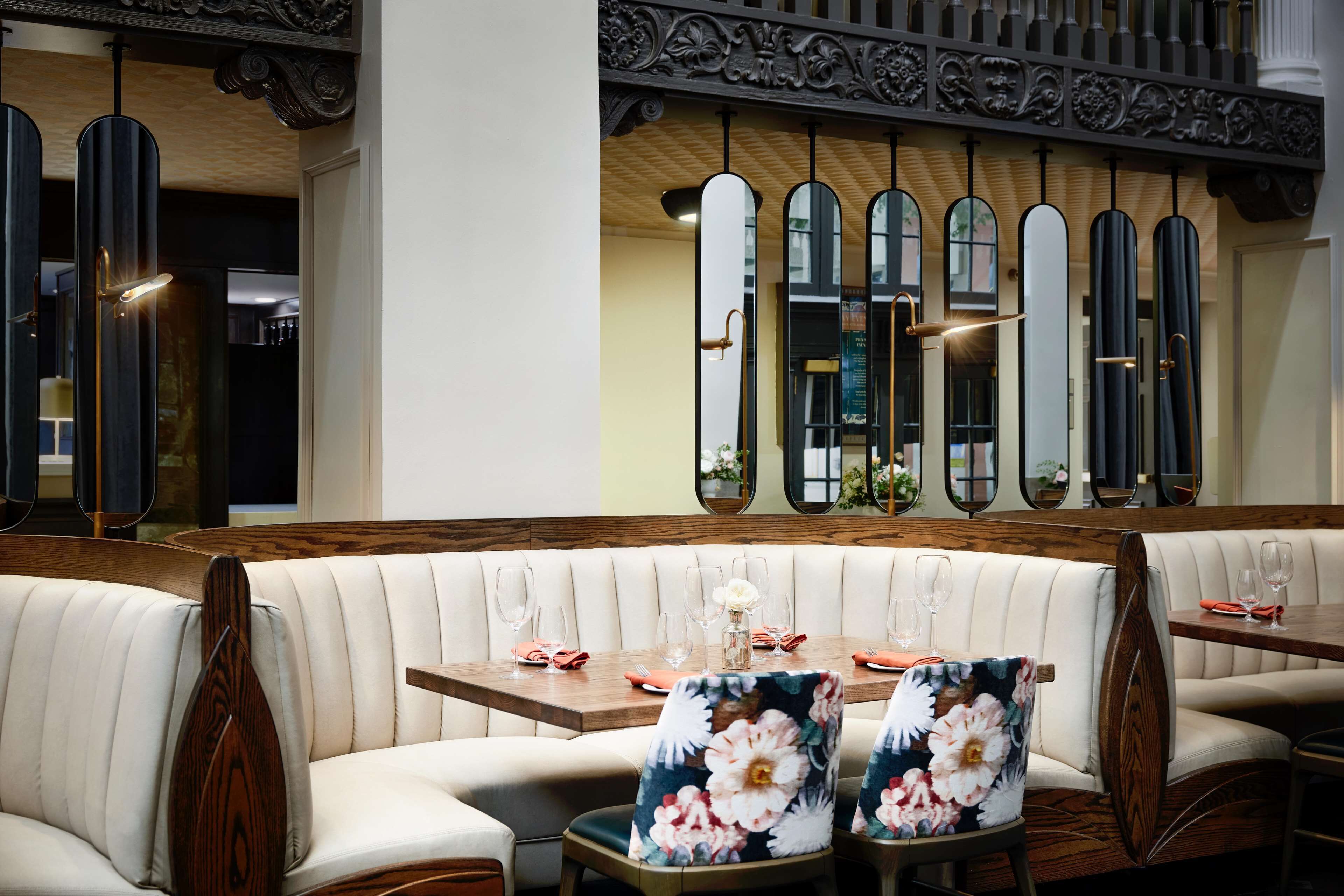 A restaurant with a wooden table and white cushioned booths.