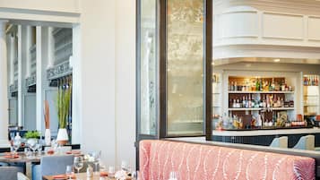 A restaurant with high ceilings, a bar area, and a seating arrangement with tables and benches.