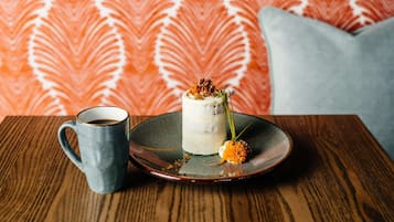 Un postre sobre un plato de cerámica con una taza de café en una mesa de madera.