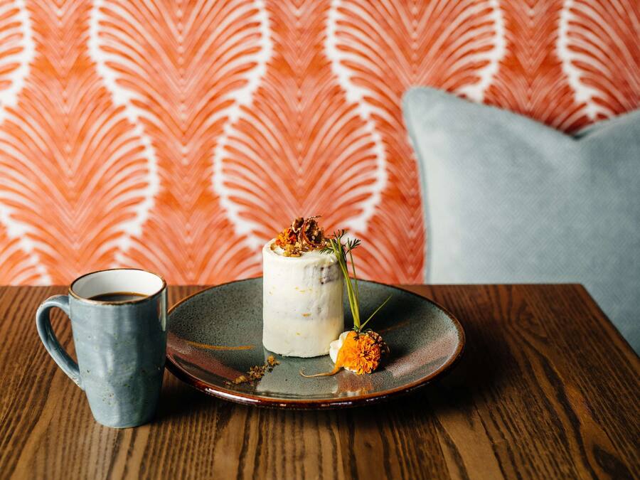 Un postre sobre un plato de cerámica con una taza de café en una mesa de madera.