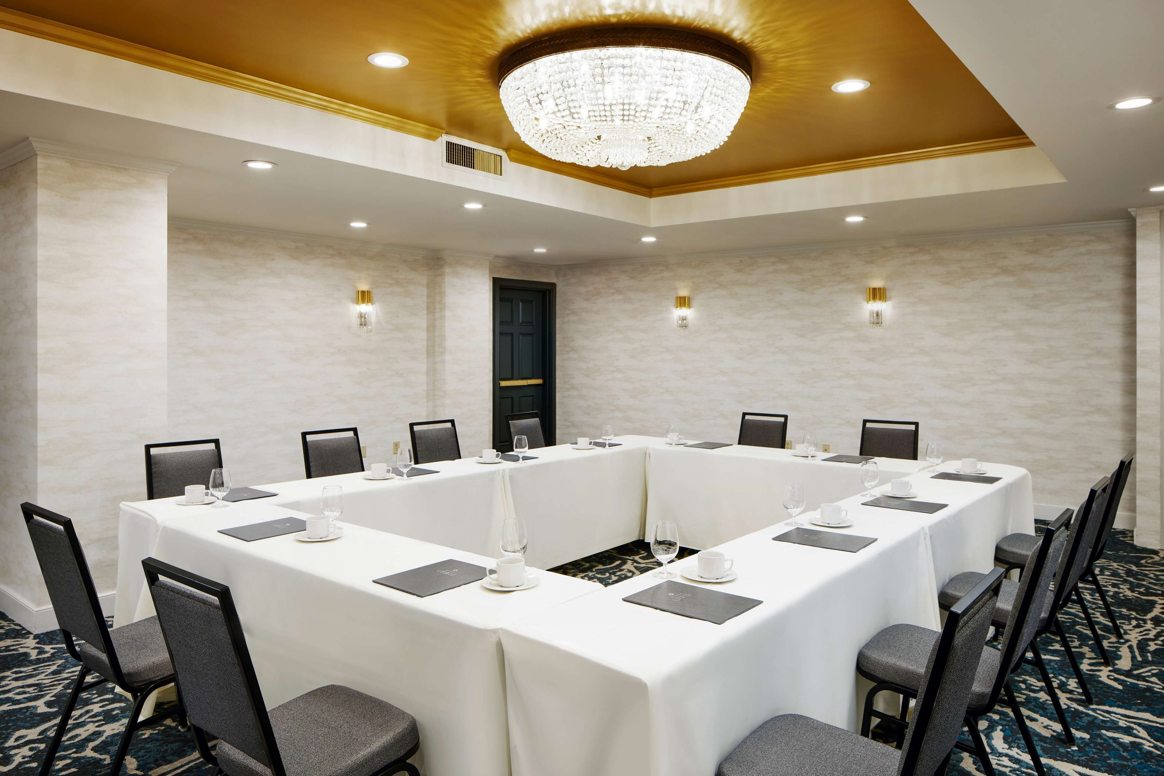 A conference room with a long table, chairs, and a chandelier.