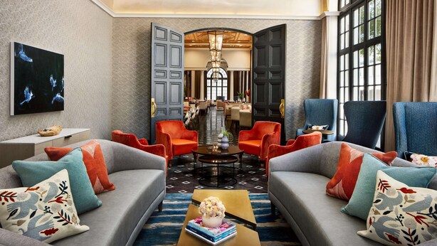 A modern living room with a sofa set, a coffee table with a decorative vase, and a large window with curtains. - The Terrace Hotel Lakeland, Tapestry Collection by Hilton (Lakeland)