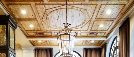 A hotel dining area with a high ceiling, large windows, and modern furniture.
