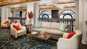A lobby with a wooden ceiling, a beige sofa, two armchairs, a coffee table, and a patterned carpet. - The Terrace Hotel Lakeland, Tapestry Collection by Hilton (Lakeland)