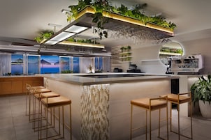 Una cocina moderna con barra, taburetes y una cafetera.