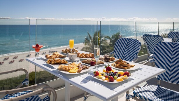 En balkon med et morgenbord med udsigt over stranden.