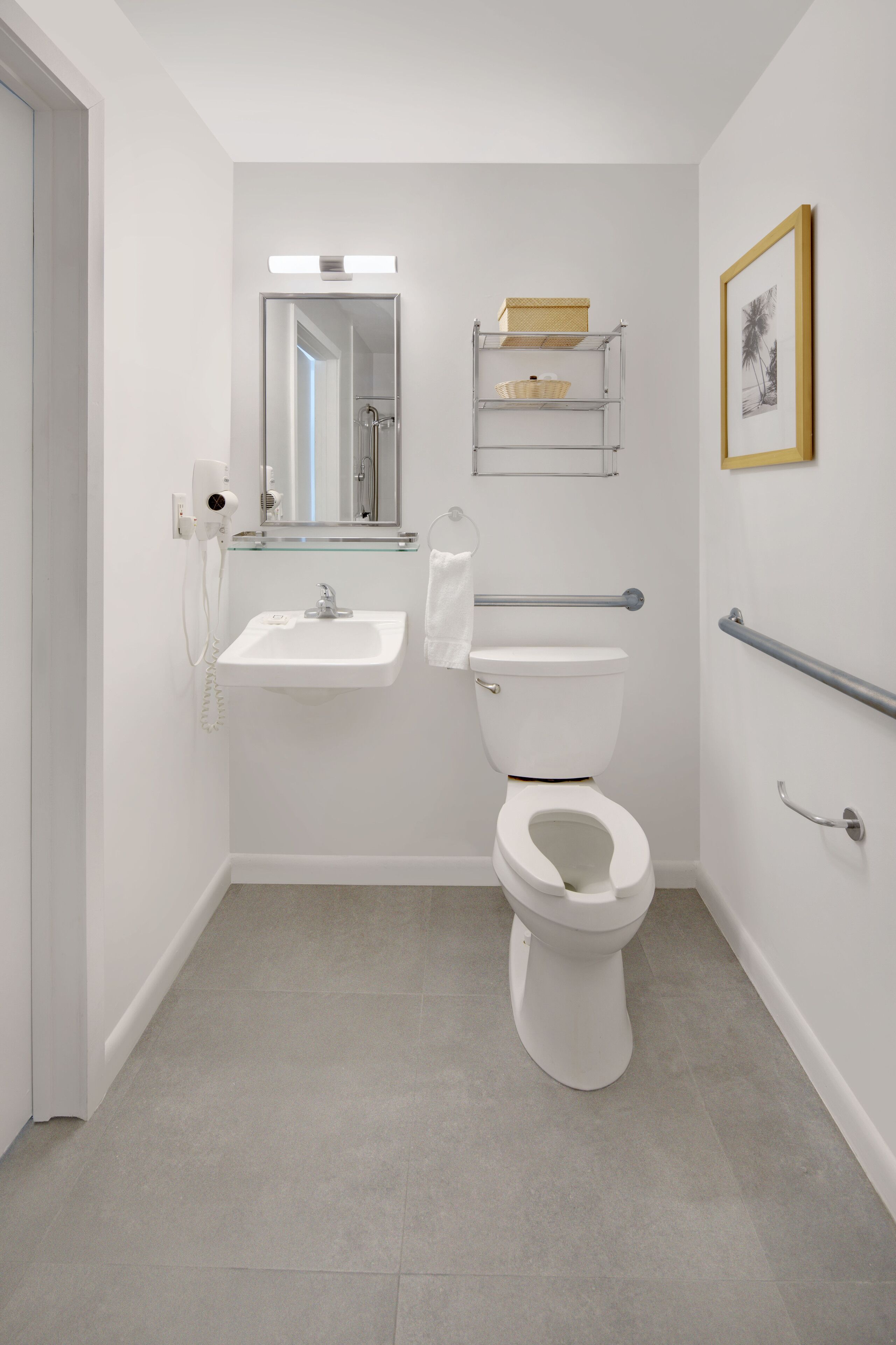 Une salle de bain moderne avec un lavabo blanc, des toilettes et une étagère en verre au-dessus du lavabo.