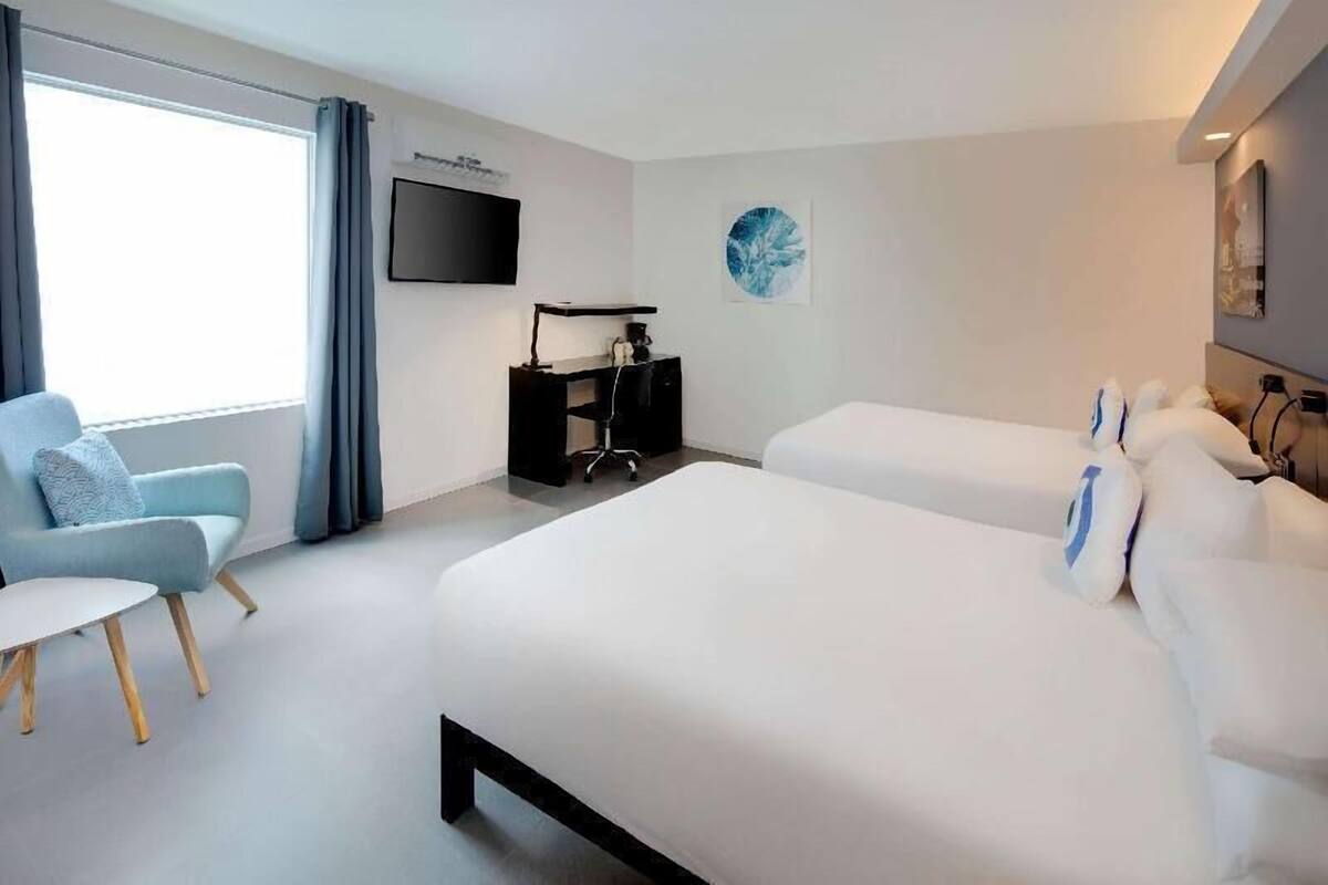 Une chambre d’hôtel avec un lit, un bureau, une chaise et un téléviseur.