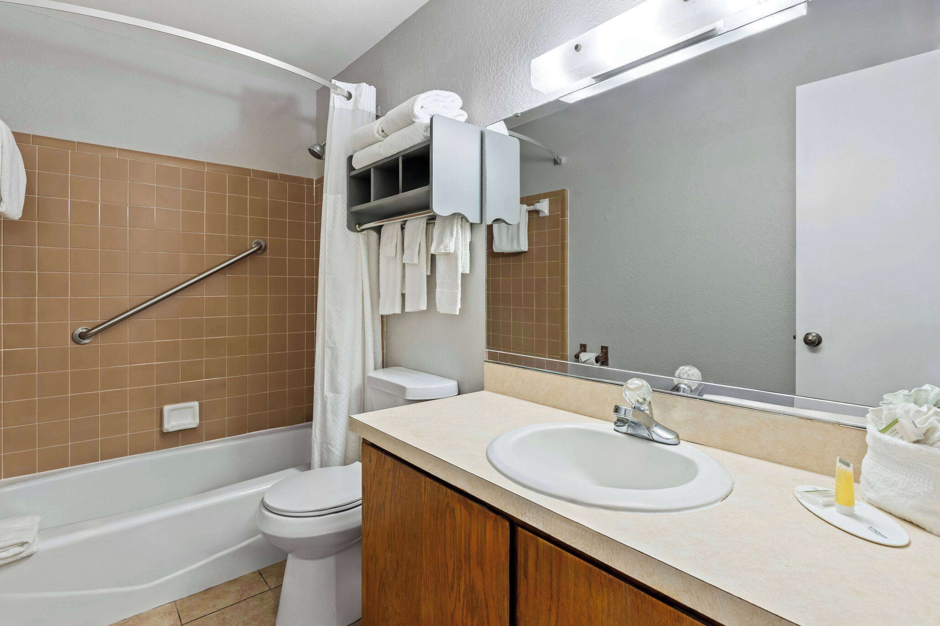 Une salle de bain moderne avec une baignoire, des toilettes et un lavabo. On y trouve un porte-serviettes avec des serviettes et un miroir au-dessus du lavabo.