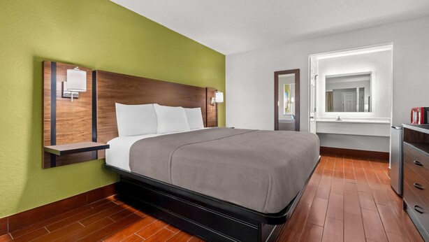 Ein Hotelzimmer mit Bett, Nachttisch, Kommode und einem Fenster mit Blick.