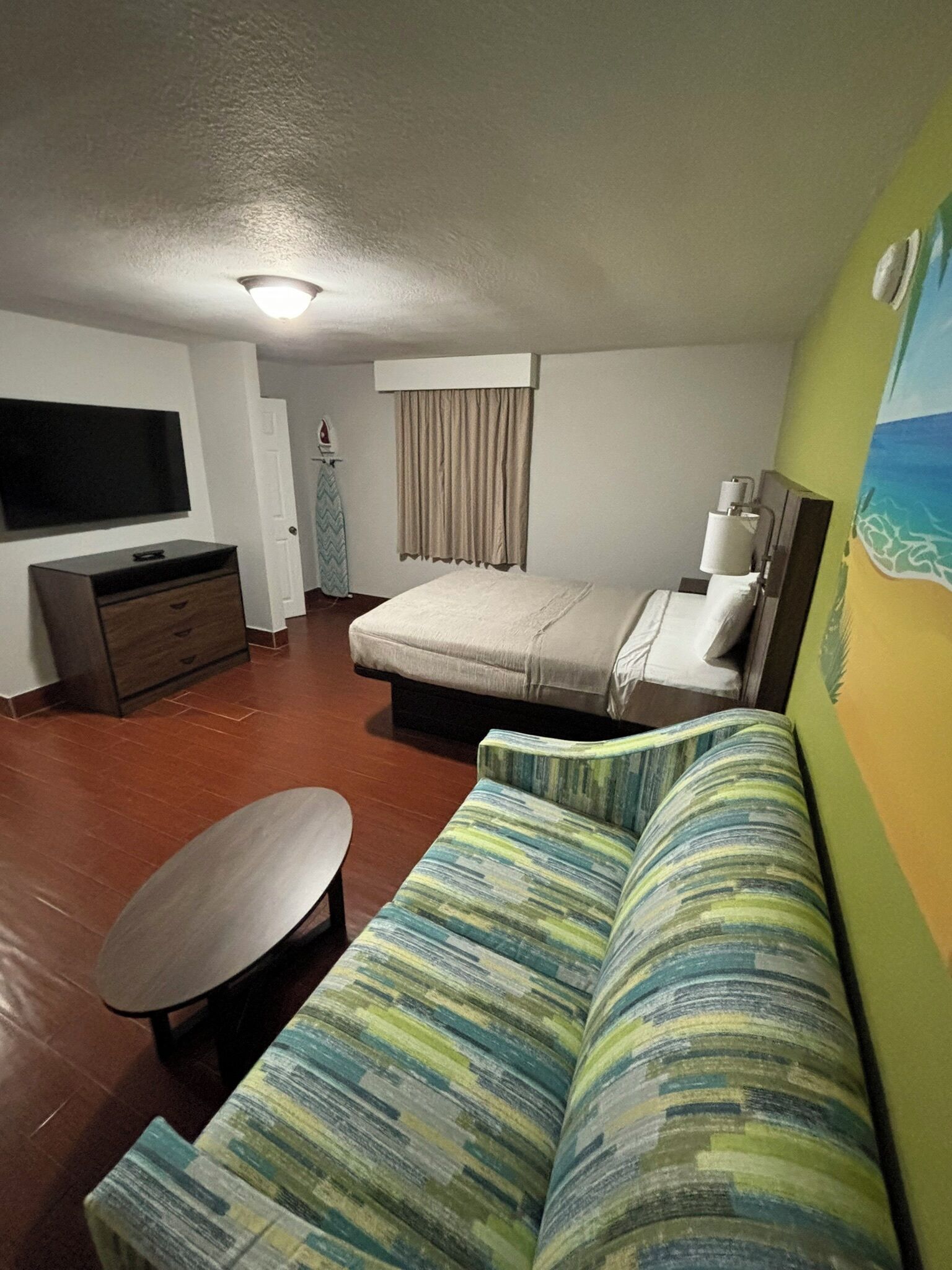 A compact living space with a bed, a sofa, a TV, and a small table.