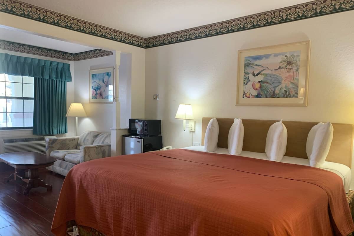 Habitació d'hotel amb un llit gran, una taula de treball, una cadira, microones, frigorífic i un quadre a la paret.