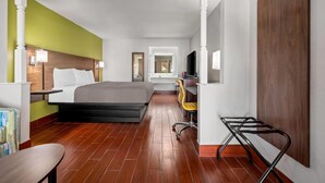 Una habitación de hotel con cama, escritorio, silla y televisor.